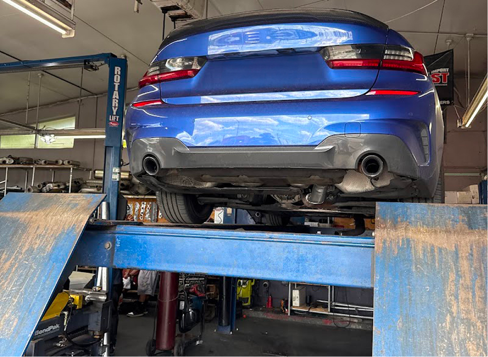Blue BMW sedan on a hydraulic lift in a garage, rear view. | King Mufflers