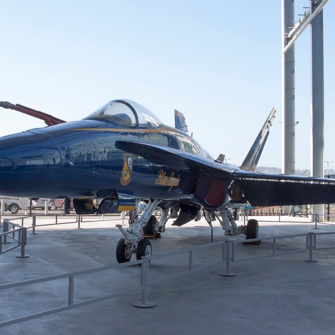 A blue fighter jet is parked in a parking lot
