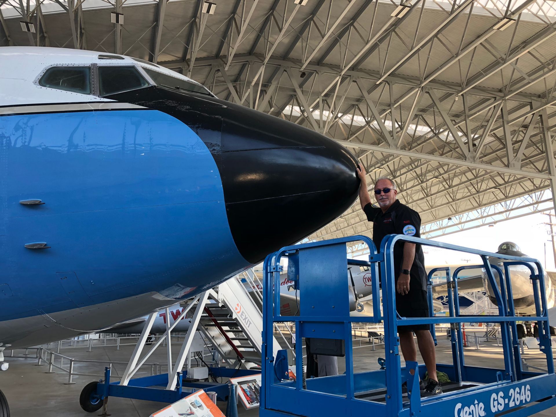 A man is standing on a lift in front of an airplane.