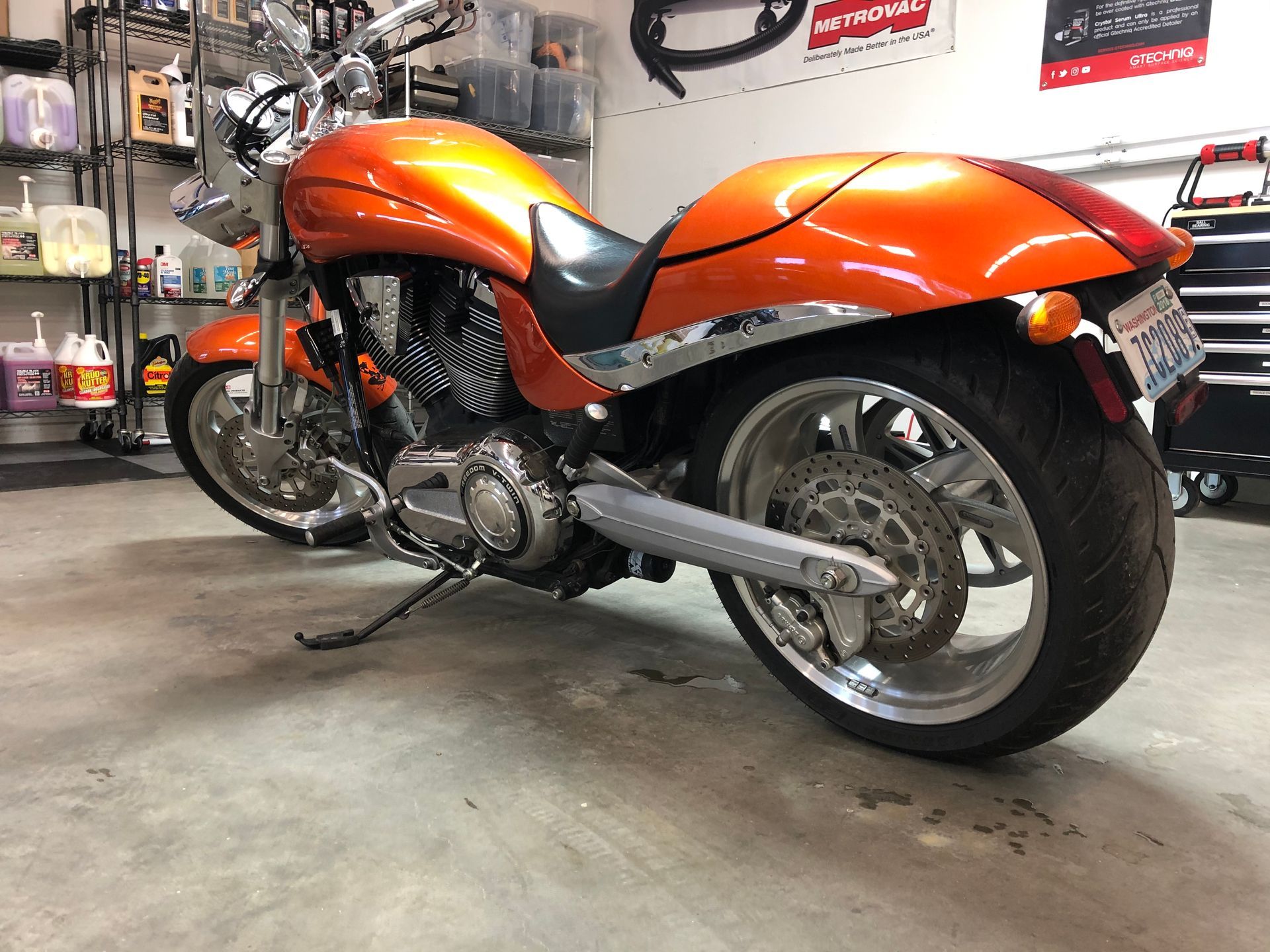 An orange victory motorcycle is parked in a garage