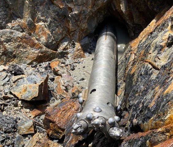 A metal pipe is sticking out of a hole in the rocks