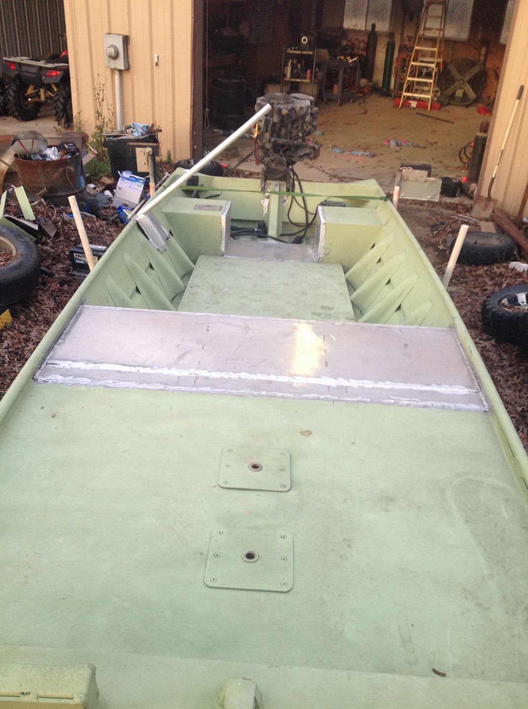 Green aluminum boat interior with metal welded sections, outside a building.
