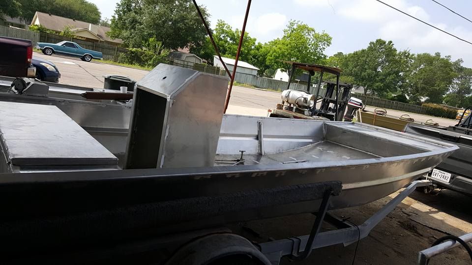 Aluminum boat on a trailer, with a center console, parked outdoors on a sunny day.