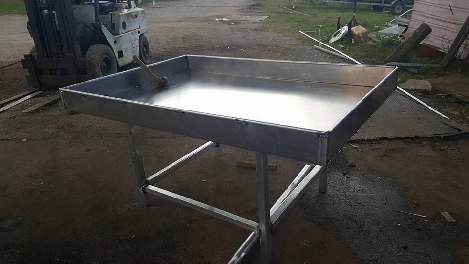 Stainless steel table on metal legs, outdoors near a forklift.