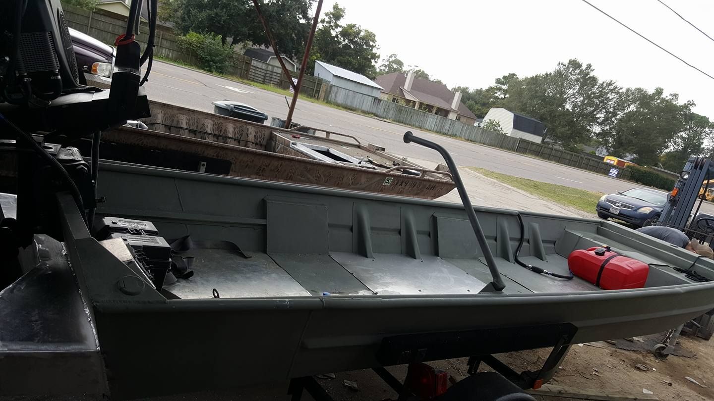 Green aluminum jon boat on trailer, with a red gas tank inside.