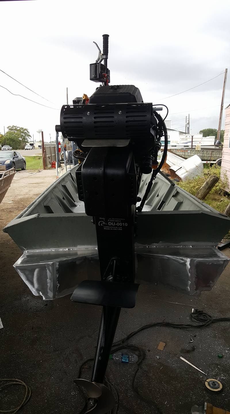 Black motor mounted on the back of a small, aluminum boat.