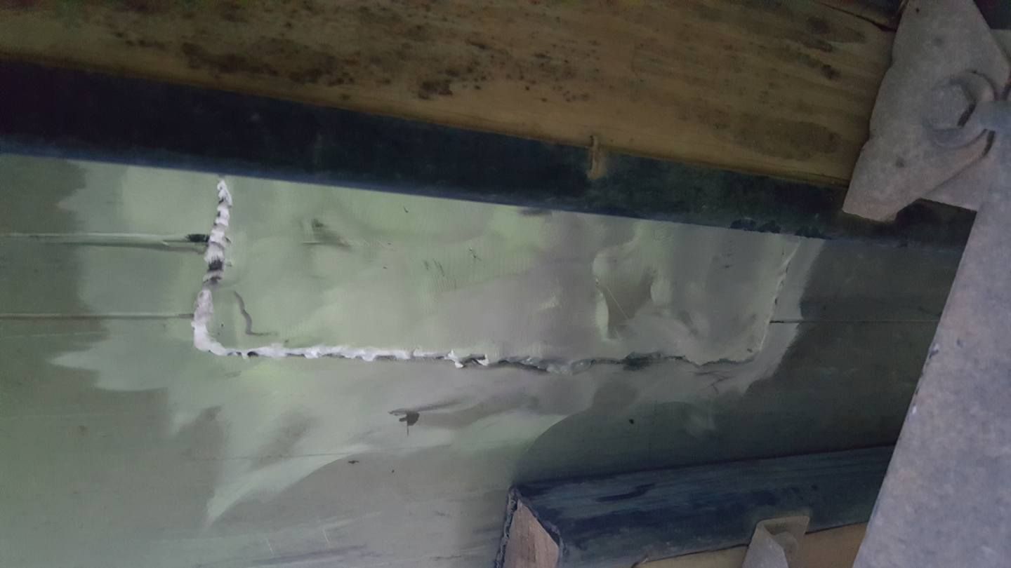 Cracked wall with white substance filling the gaps. Dark wood and flooring visible.