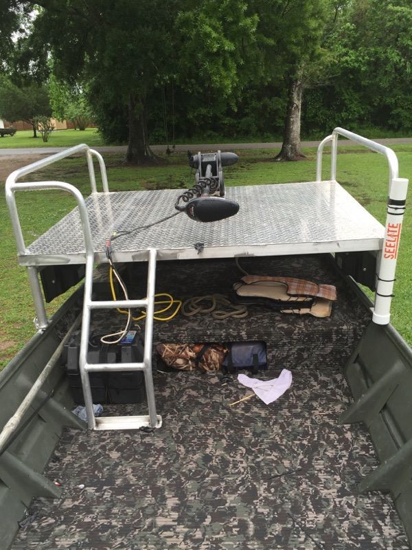 A boat with a metal platform and ladder; a trolling motor is mounted on it.