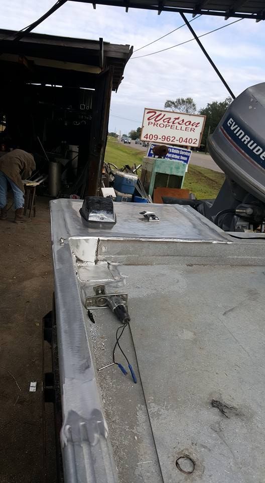 Aluminum boat with Evinrude motor, next to a repair shop.