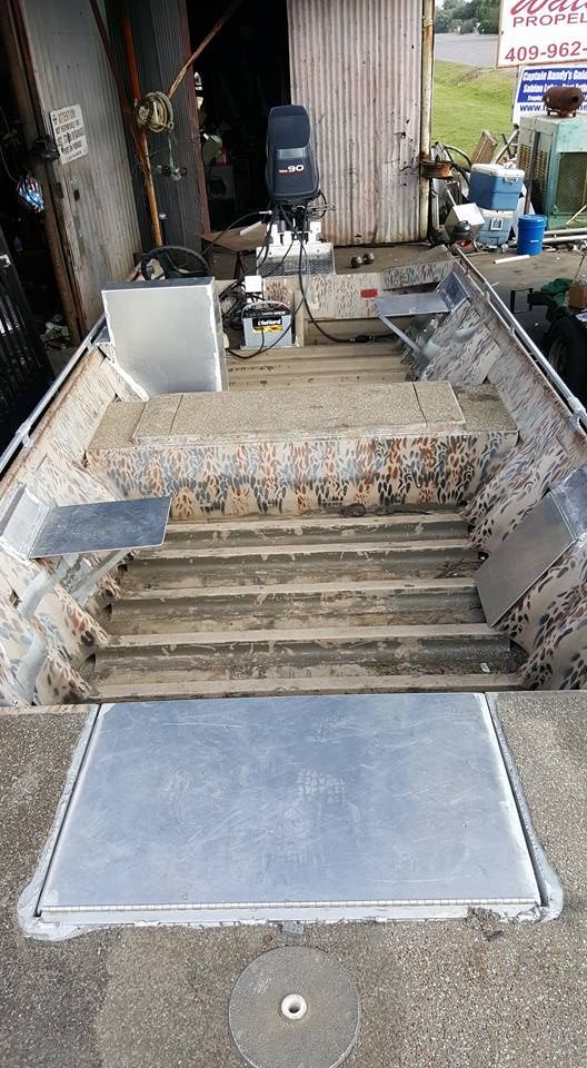 An open, weathered aluminum boat with an outboard motor, likely used for fishing.