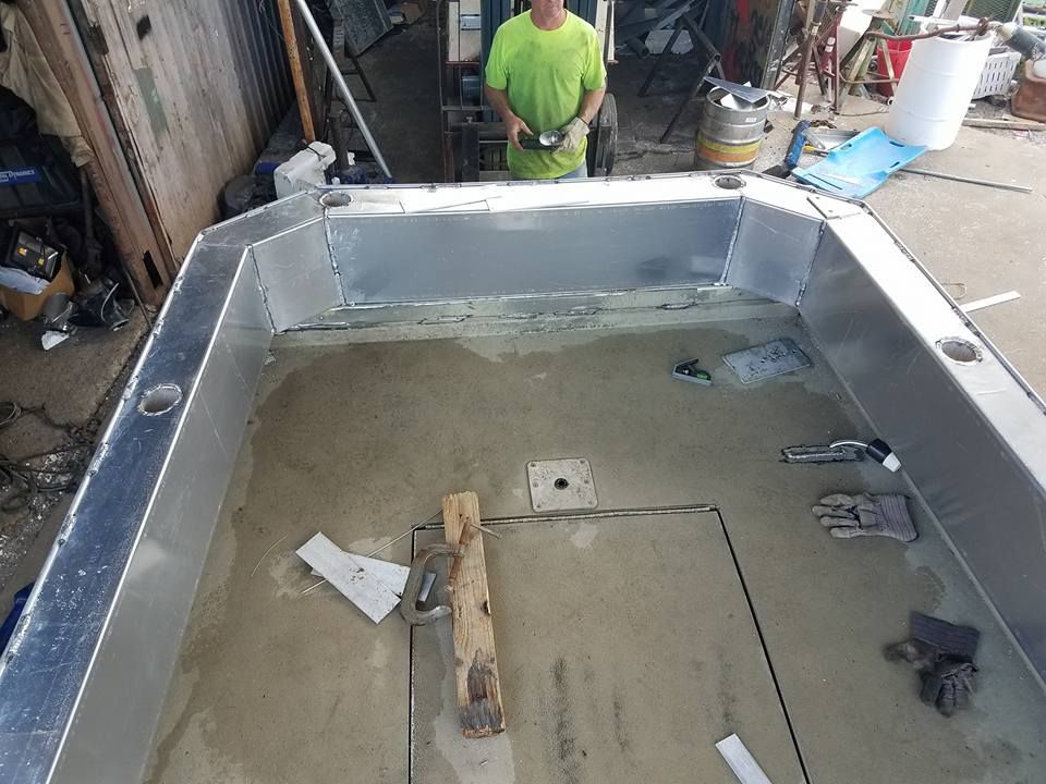 Man working on a boat interior with metal edging, surrounded by tools and materials.