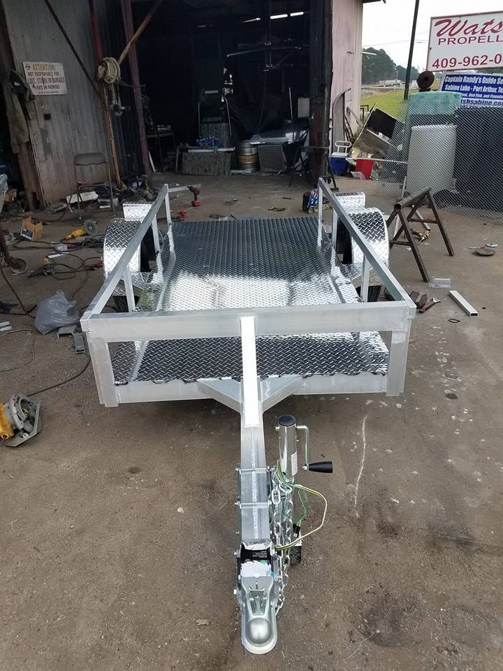 New aluminum utility trailer with a checkered floor, resting on a concrete surface.