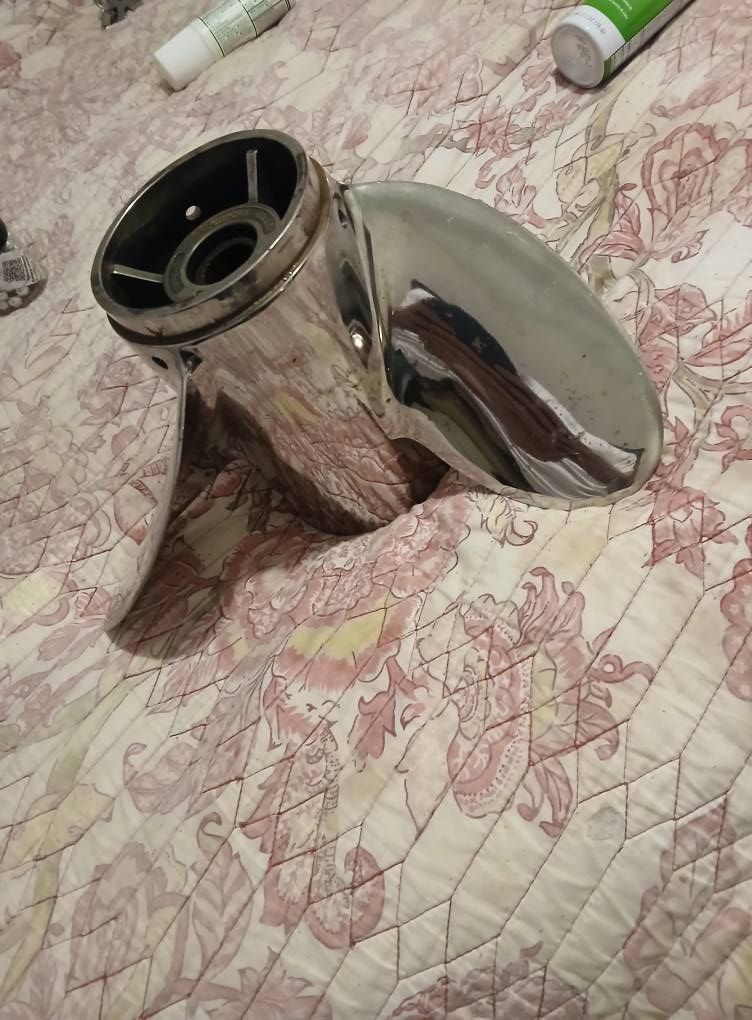 Polished stainless steel boat propeller on a floral patterned bedspread.