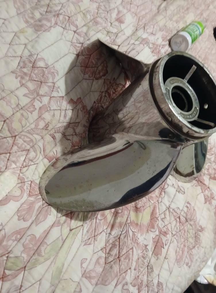 Shiny, stainless steel boat propeller on a floral patterned surface.