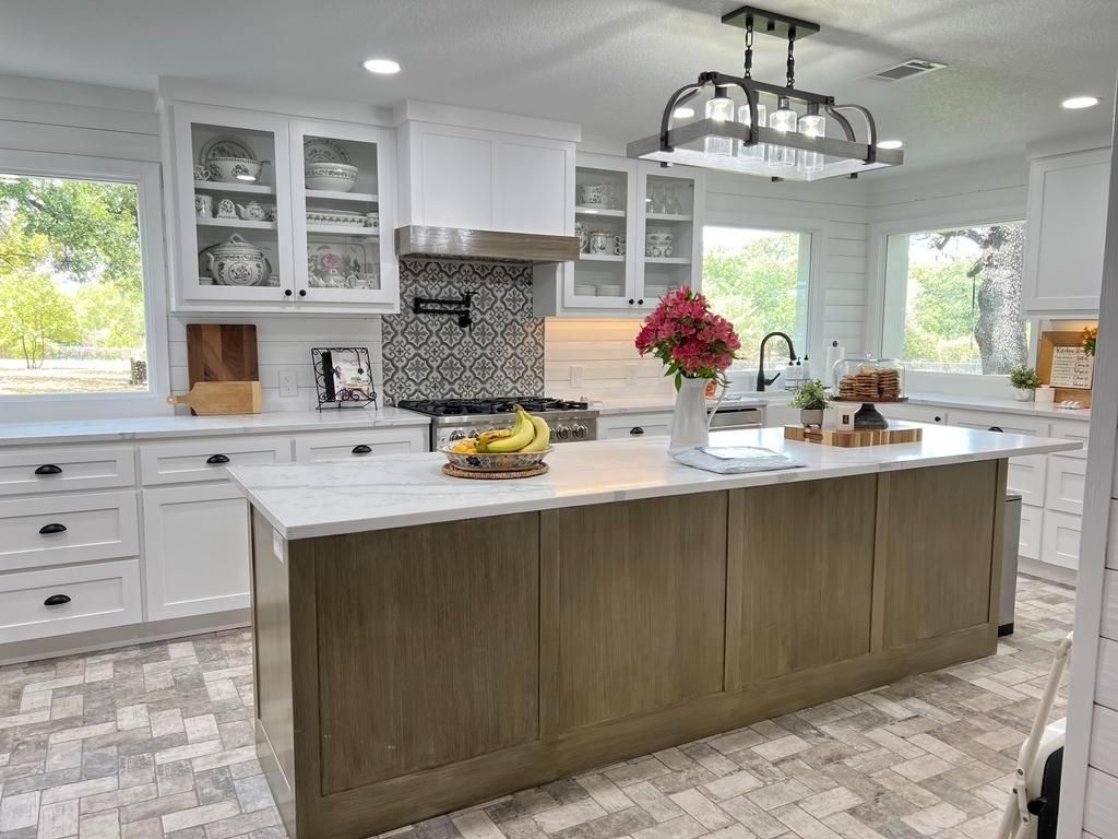 A kitchen with white cabinets and a large island in the middle.