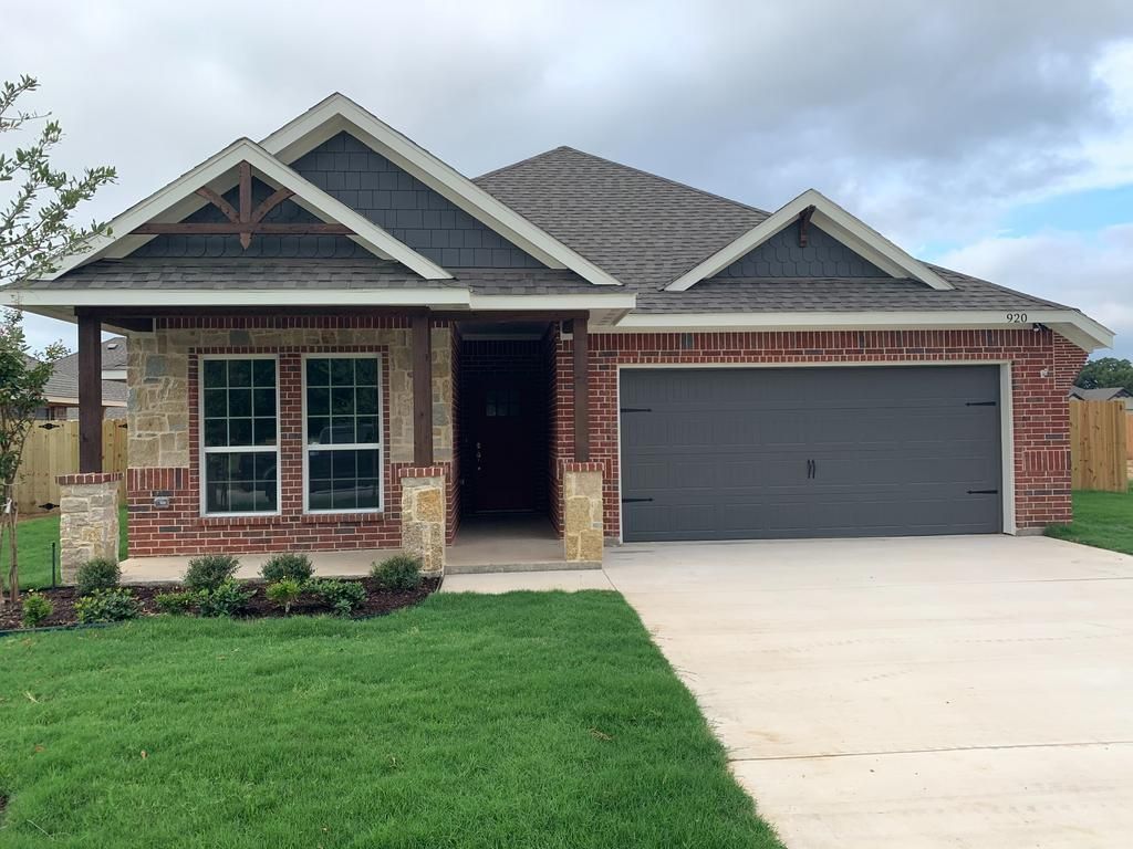 A brick house with a gray garage door is for sale.