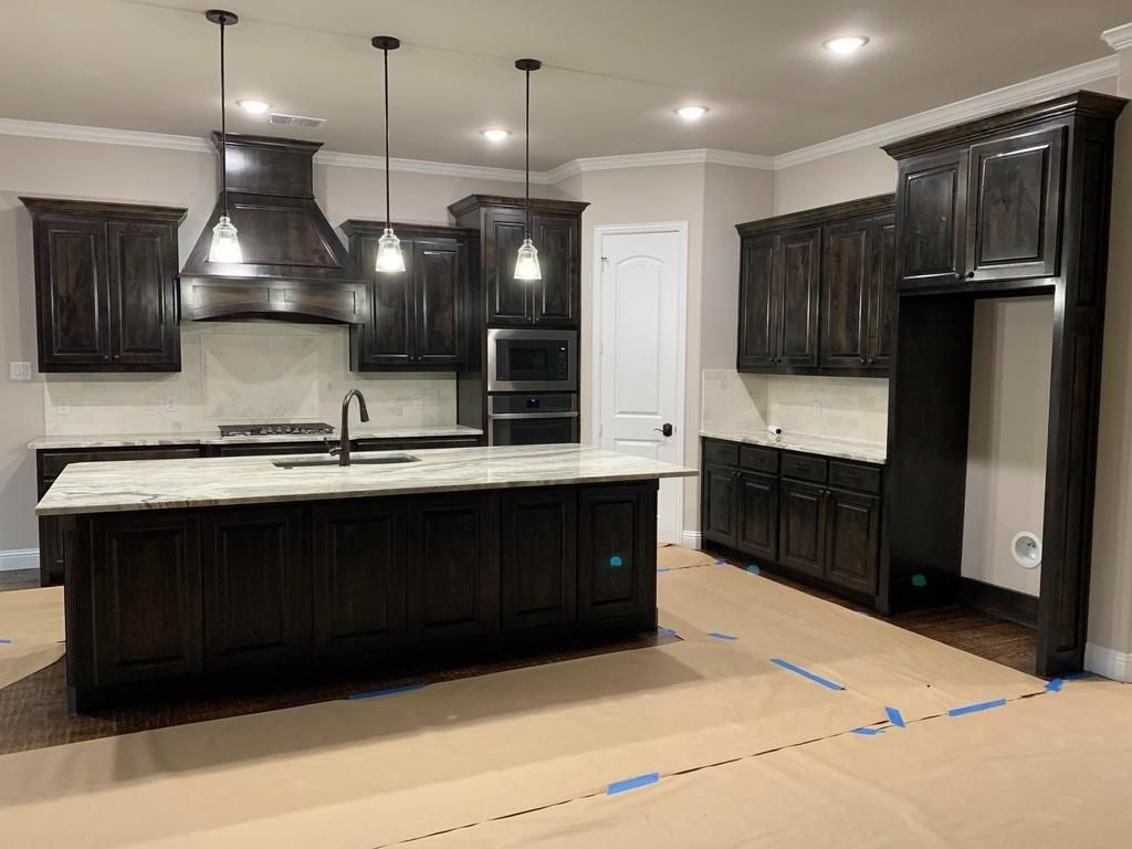 A kitchen with black cabinets and a large island in the middle.