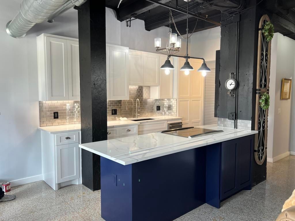 A kitchen with white cabinets and a blue island.