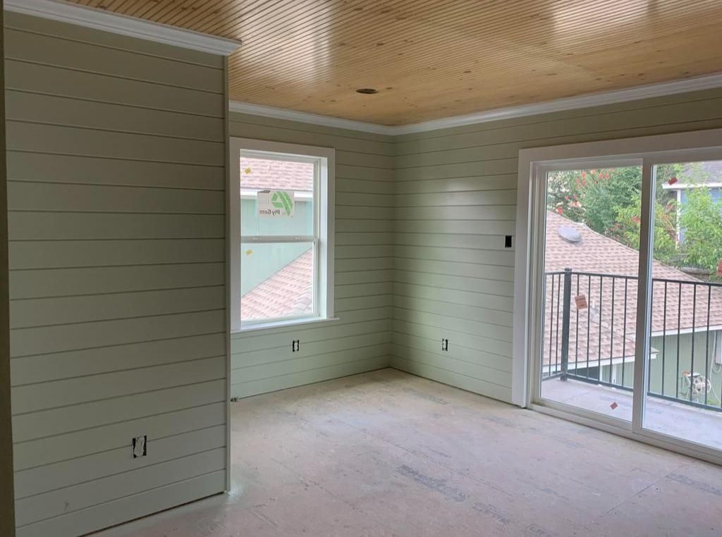 A large empty room with a balcony and sliding glass doors.