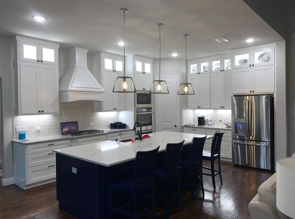 A kitchen with white cabinets and stainless steel appliances and a large blue island.