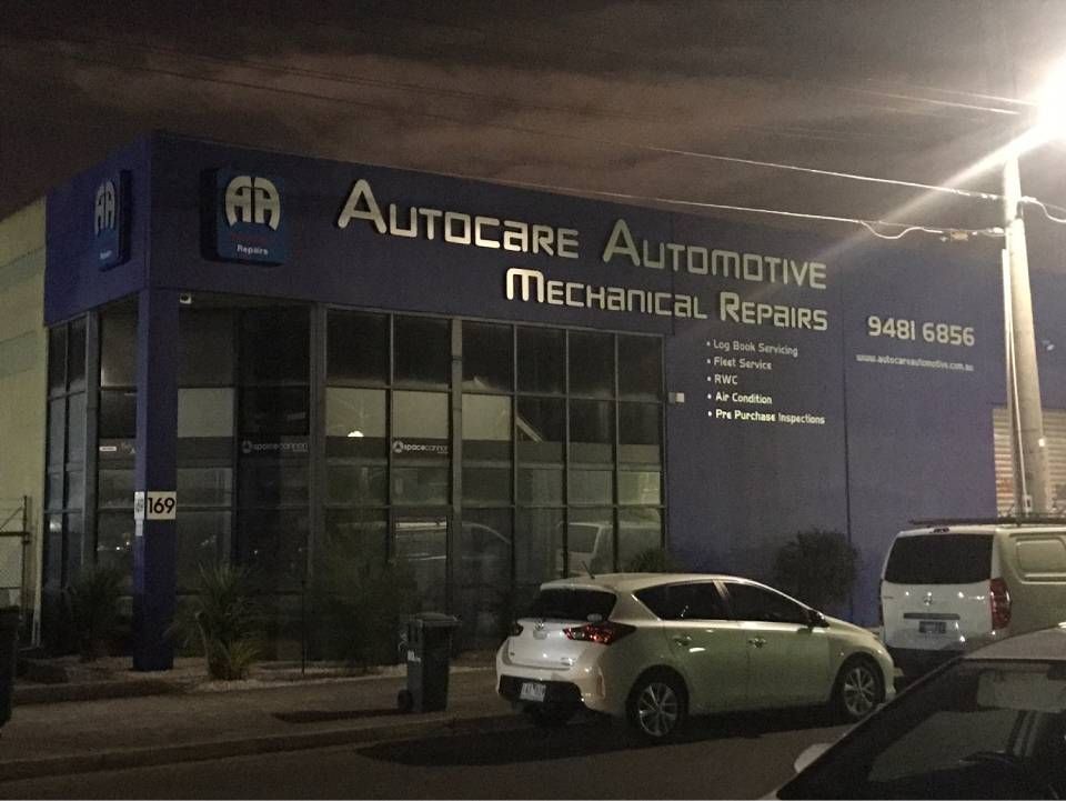 AutoCare Automotive Mechanic Repairs storefront at night, with parked cars and lit signage.