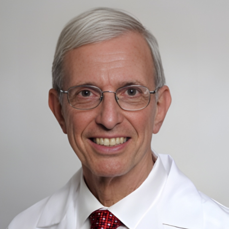 Woman in a white coat smiles, pink shirt visible, looking at the viewer.