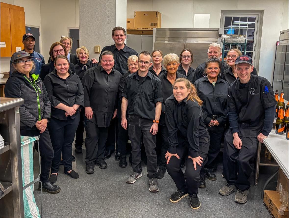 A group of chefs are posing for a picture in a kitchen.