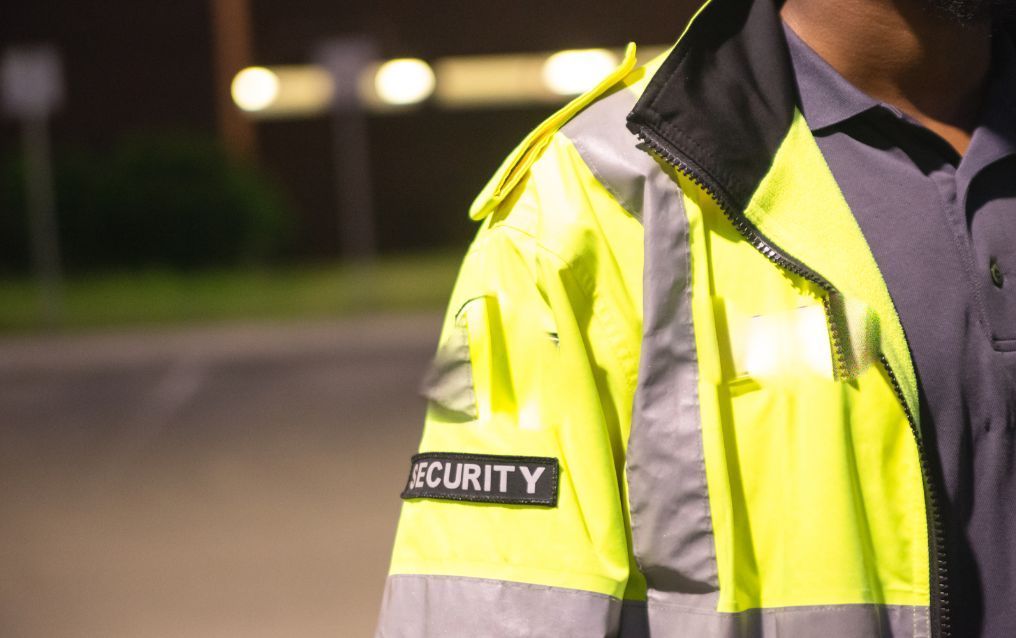 A security guard wearing a yellow vest with the word security on it.