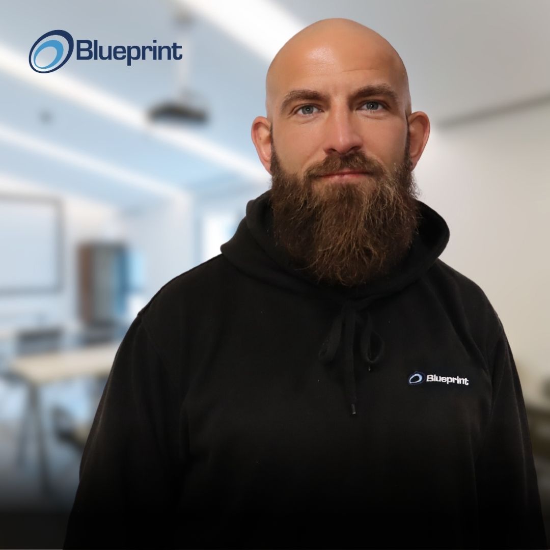 A bald man with a beard wearing a black hoodie