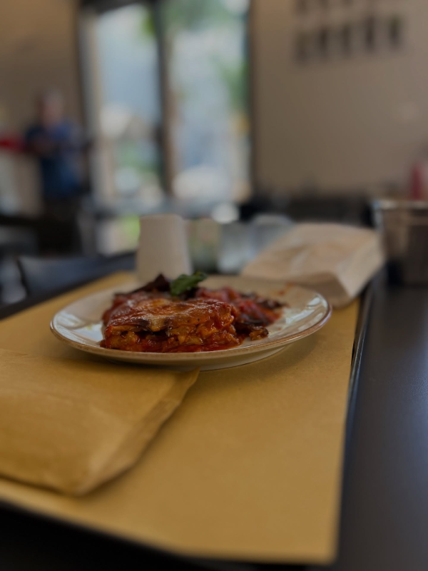 Lasagna su un piatto, su carta gialla, in un ristorante. Sfondo sfocato.