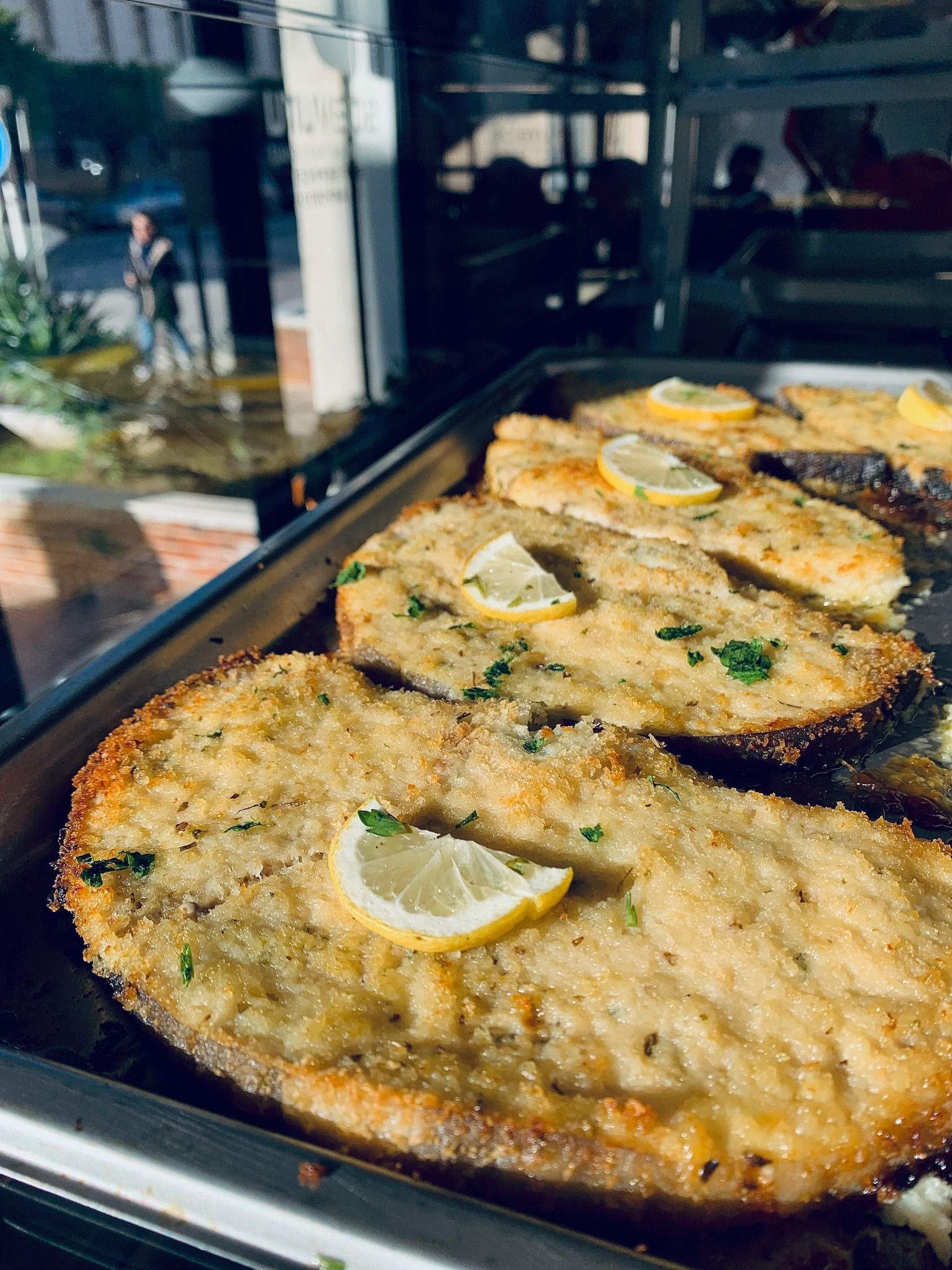 Cotolette impanate con fettine di limone, servite su un vassoio di metallo.