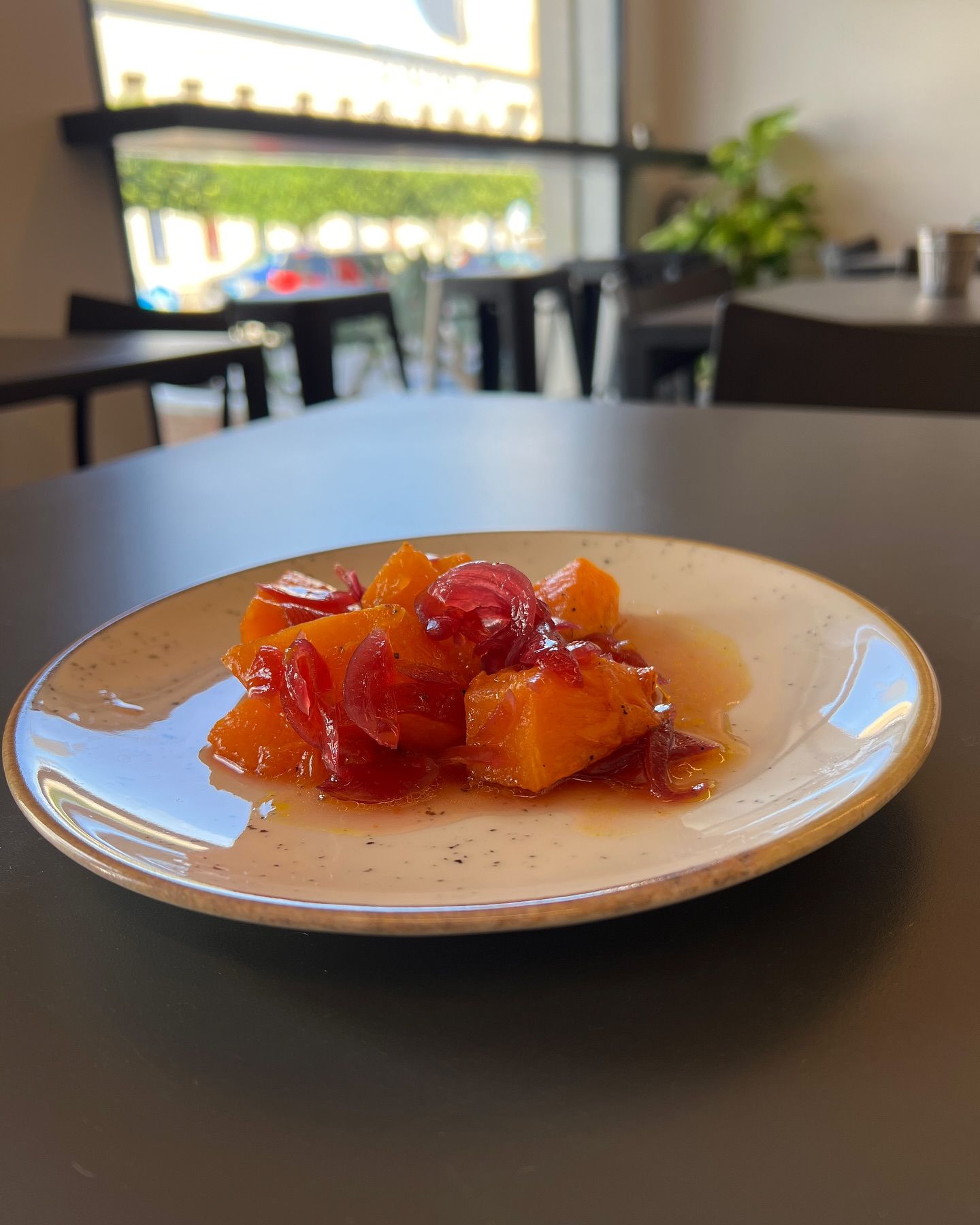 Un piatto di frutti arance e rossi con salsa su un tavolo, in un ambiente da bar.