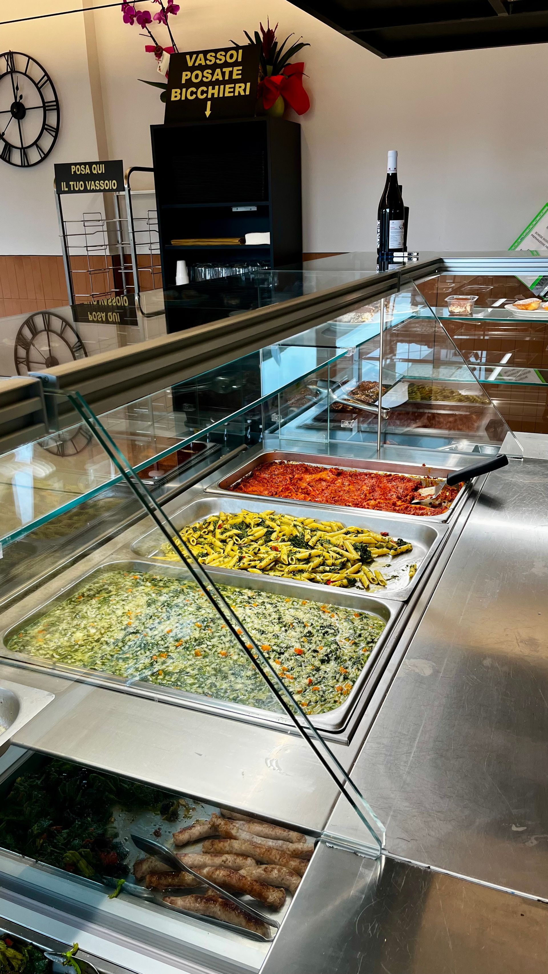 Una vetrina piena di insalate di vario tipo in un ambiente luminoso da ristorante.