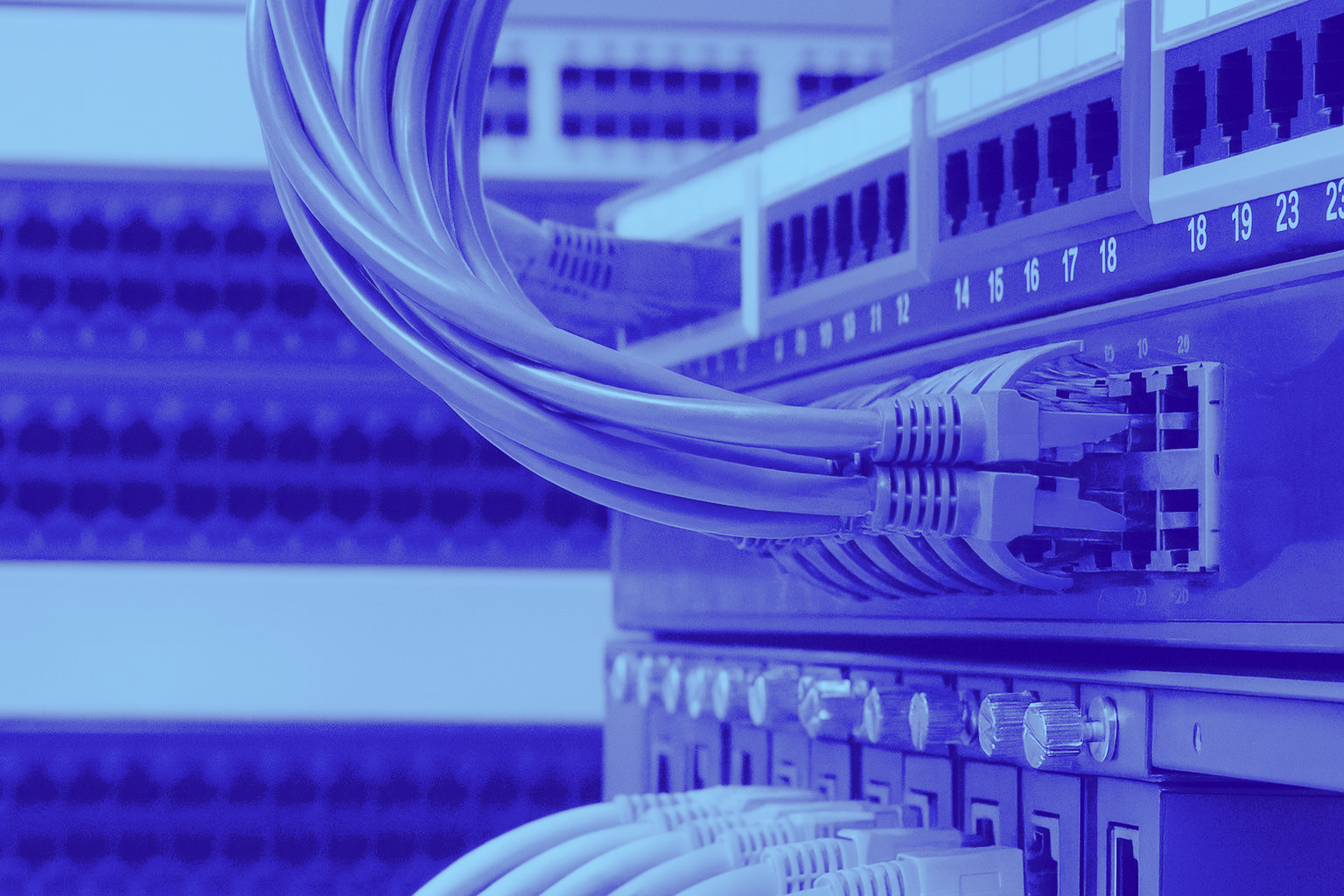 Blue-tinted rack of network switches with Ethernet cables connected.