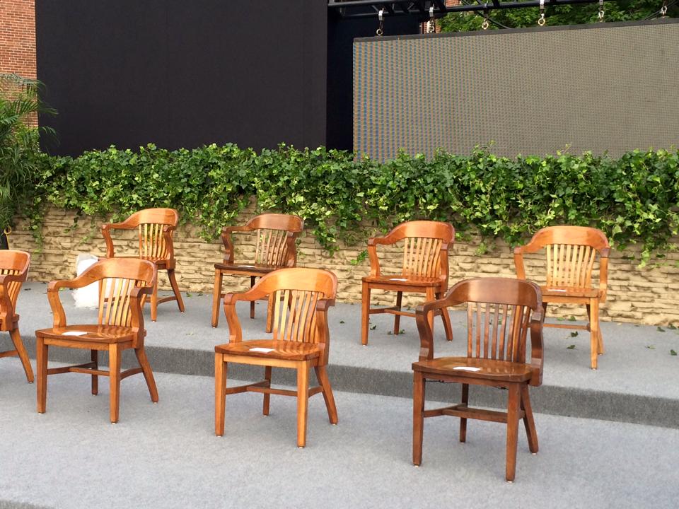 a row of wooden chairs in front of a stone wall