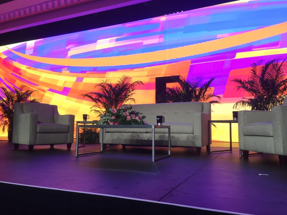a stage with chairs and a couch in front of a colorful wall