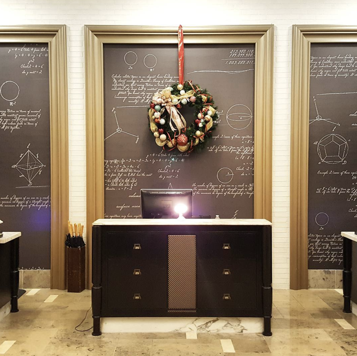 a christmas wreath hangs on a wall above a desk