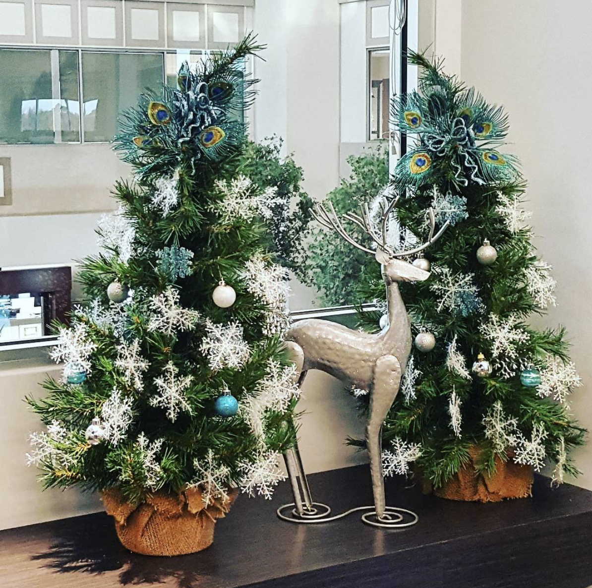 two christmas trees and a deer on a table