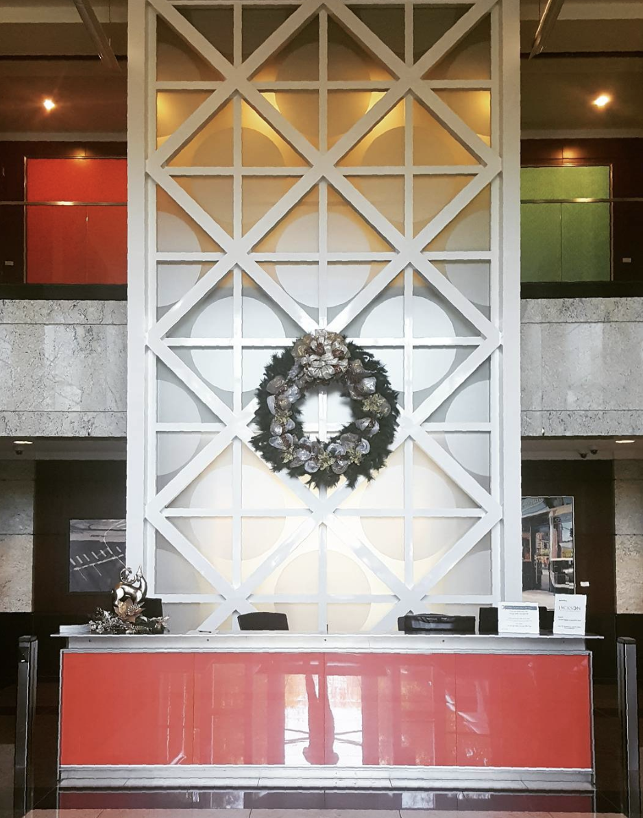 a christmas wreath hangs above a red counter in a lobby