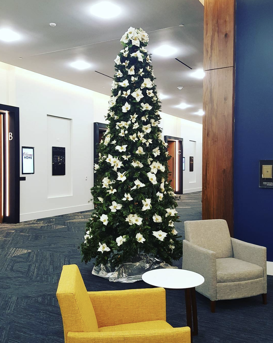 a christmas tree in a hallway with chairs and a table