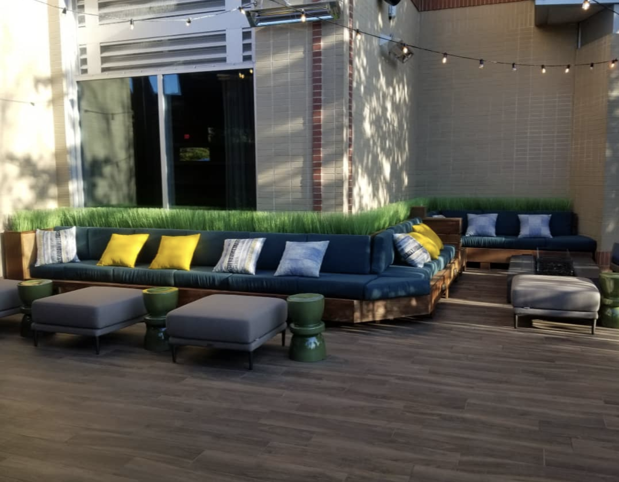 a large couch with yellow pillows sits on a wooden deck