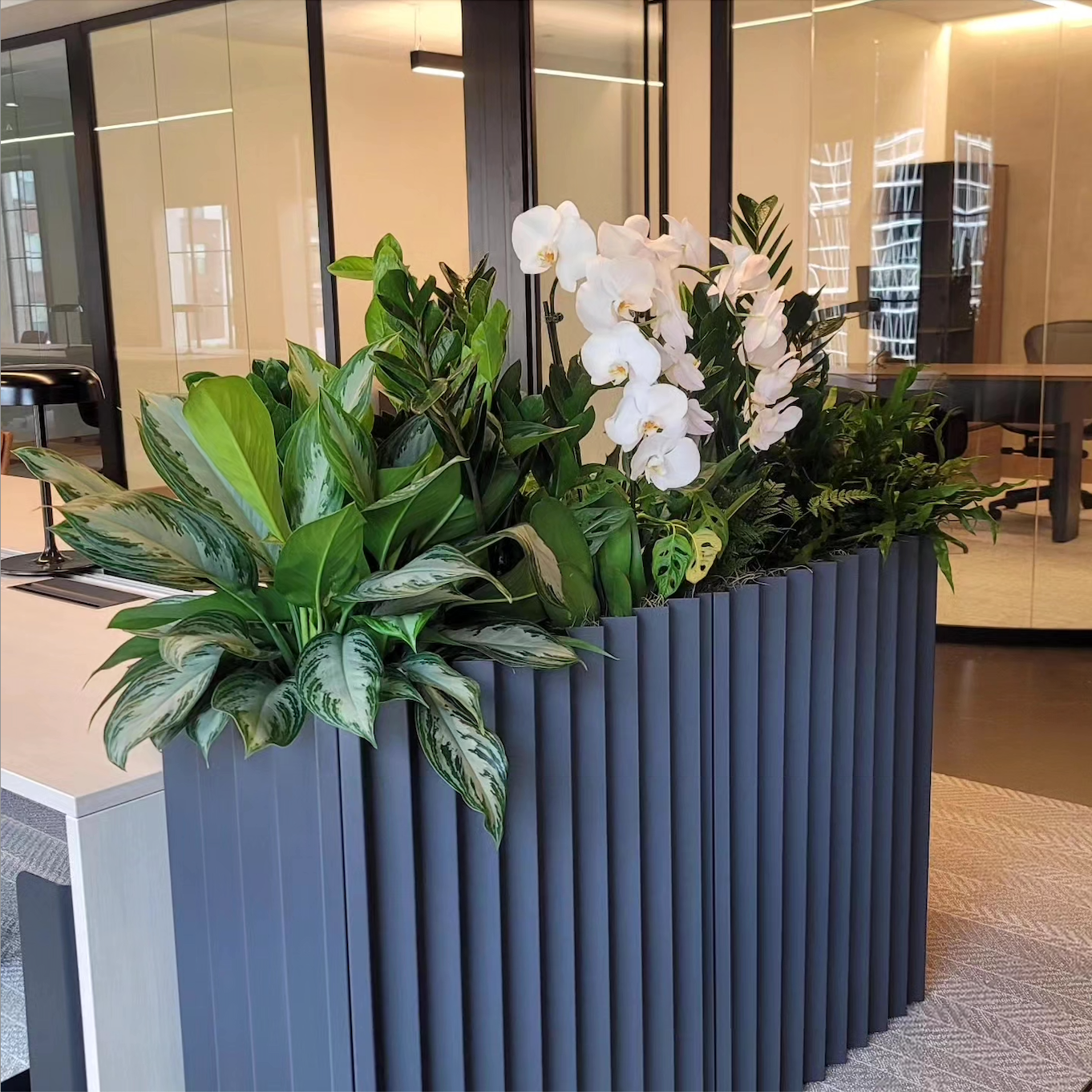 a black planter filled with plants and flowers in an office