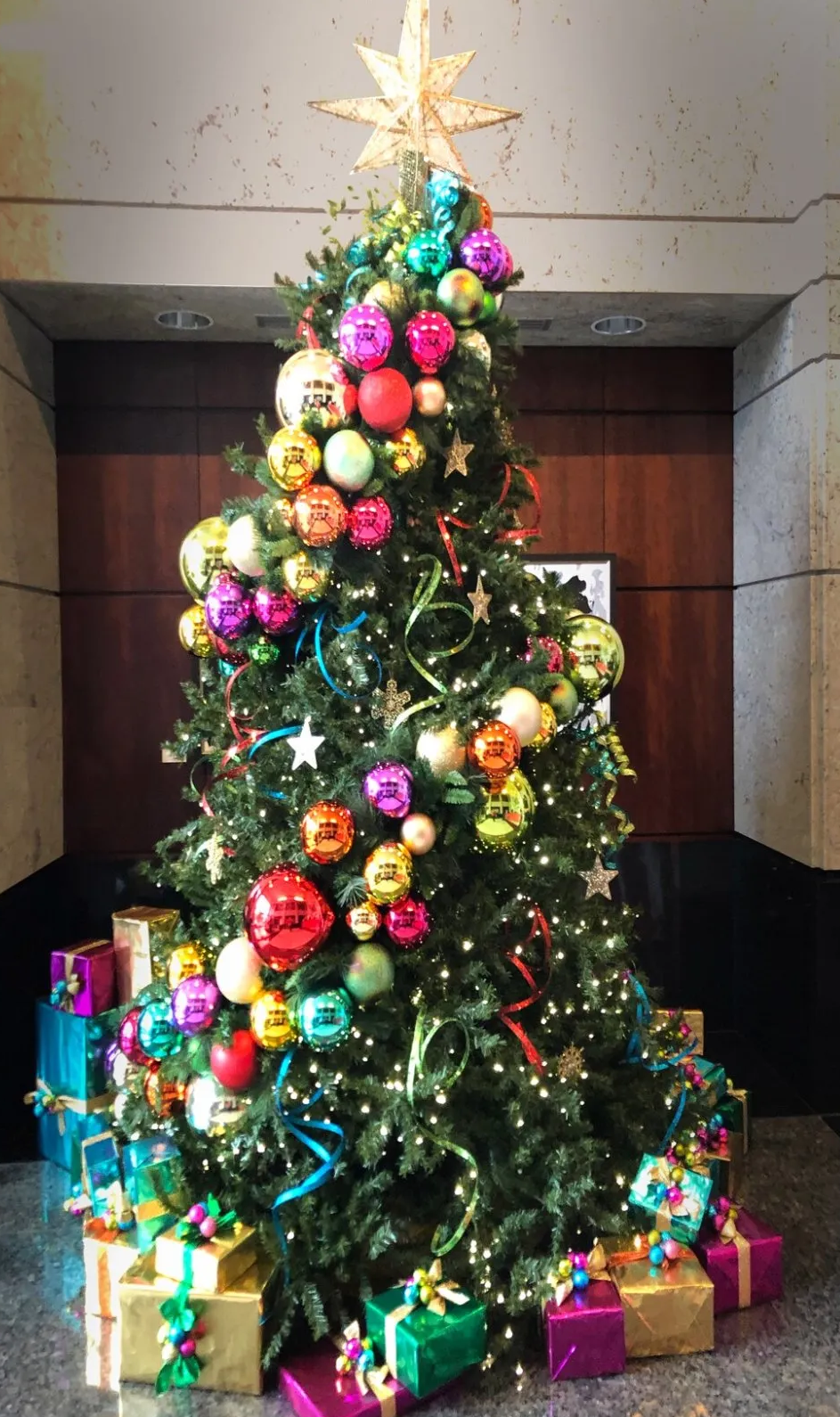 a christmas tree is decorated with lots of colorful ornaments and gifts