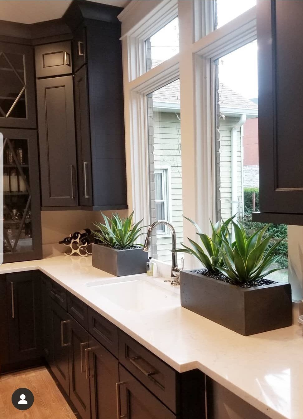 a kitchen with black cabinets , white counter tops, and a sink