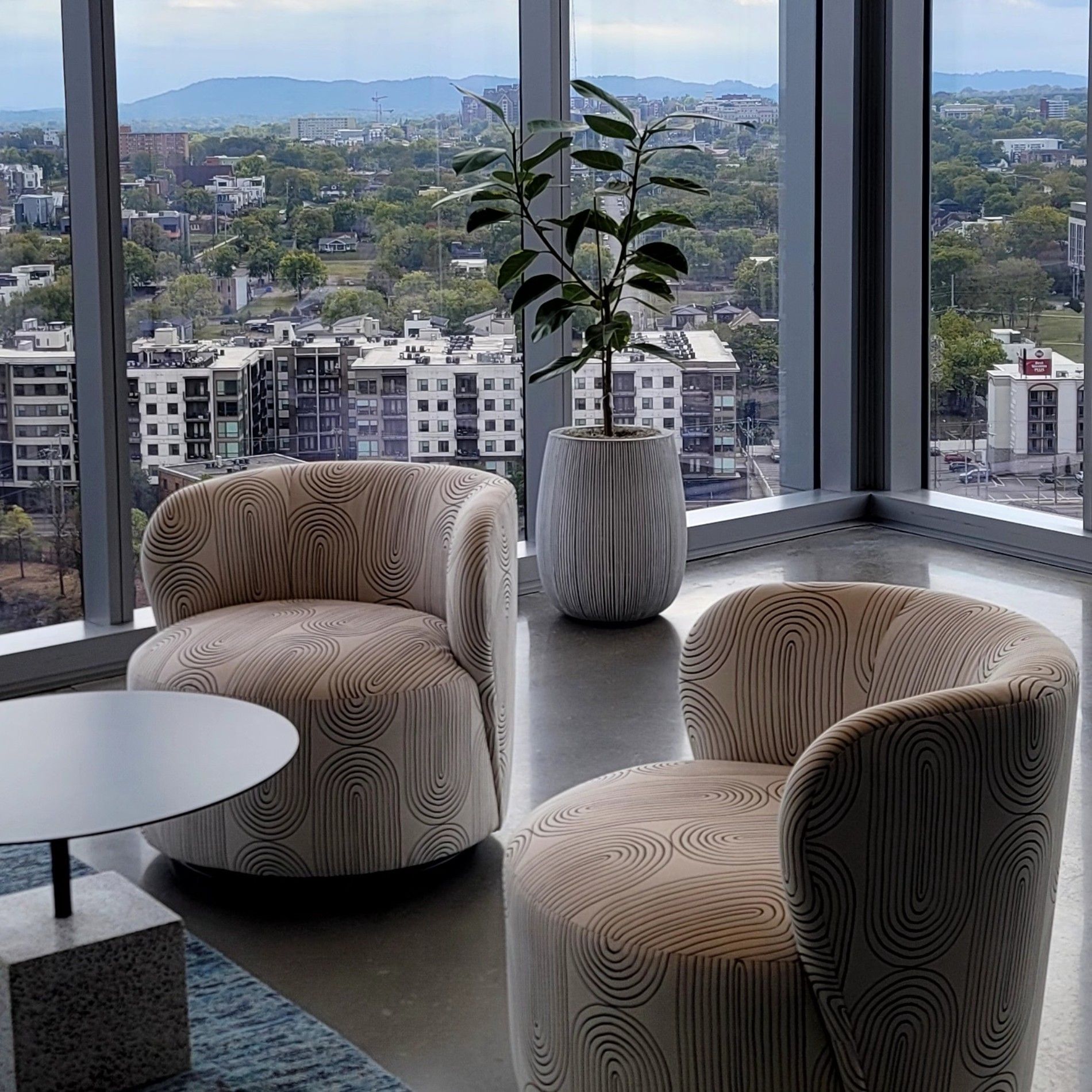 a living room with two chairs and a table with a view of a city