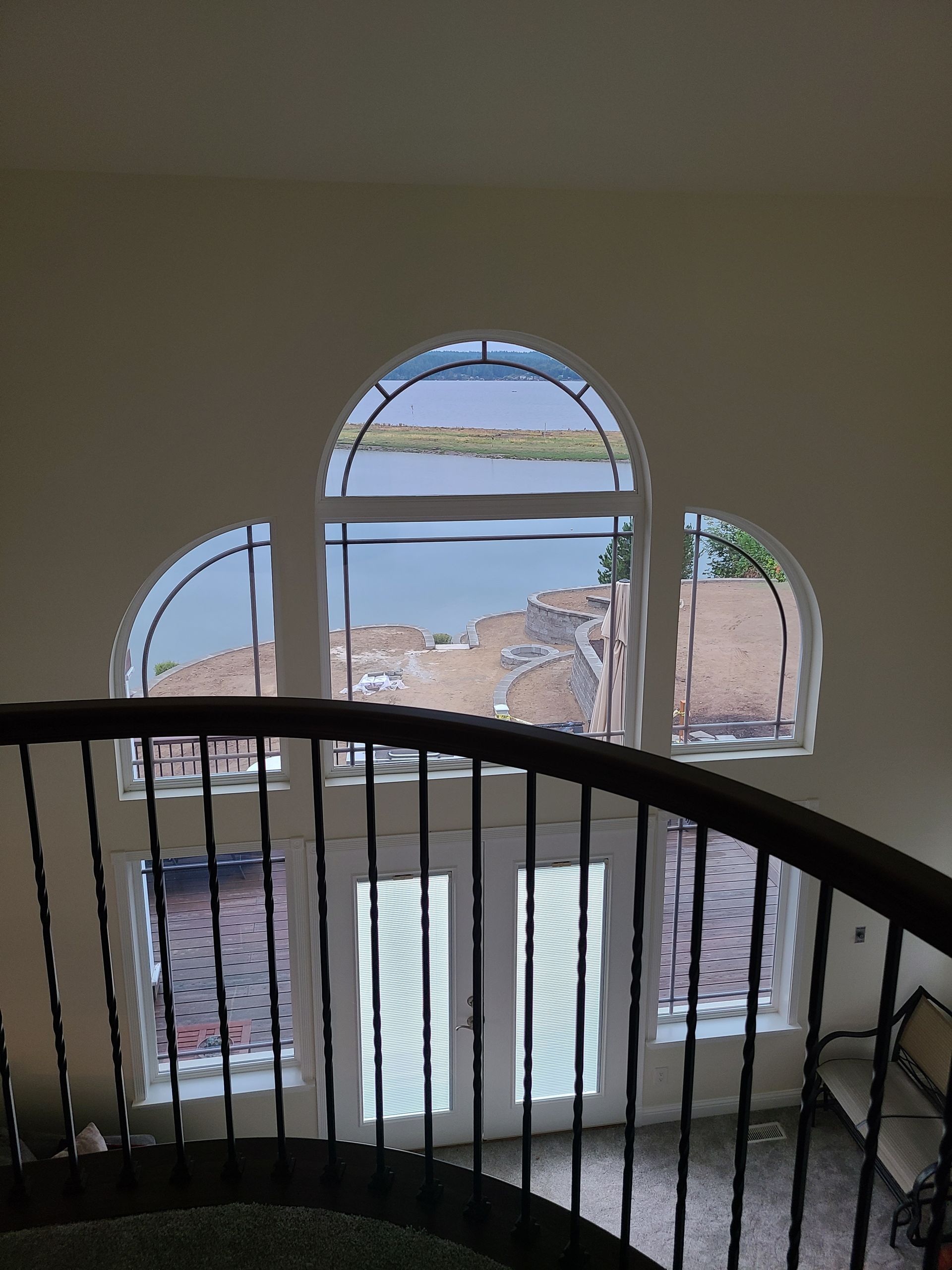 Interior view from a curved stairwell, looking at arched windows overlooking a hillside.