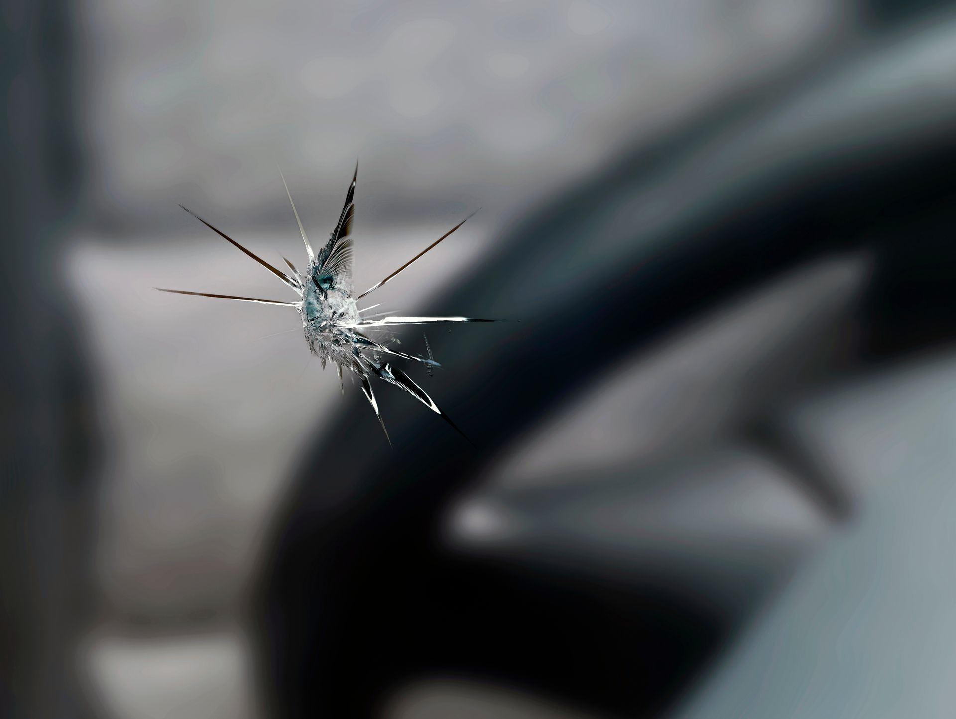 A windshield with a star-shaped crack, steering wheel in soft focus in background.