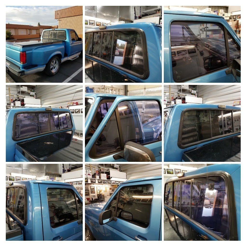 A person installing car window tint on a black vehicle.