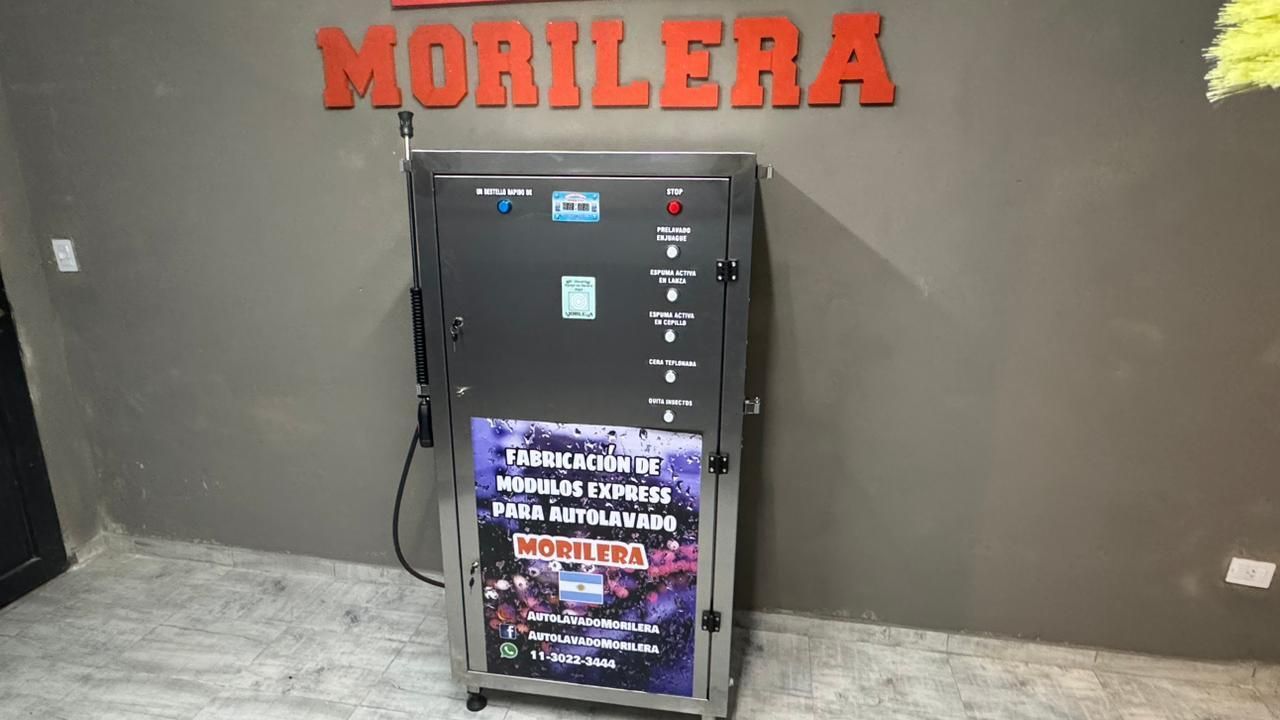 Máquina expendedora metálica frente a una pared con un letrero rojo que dice 