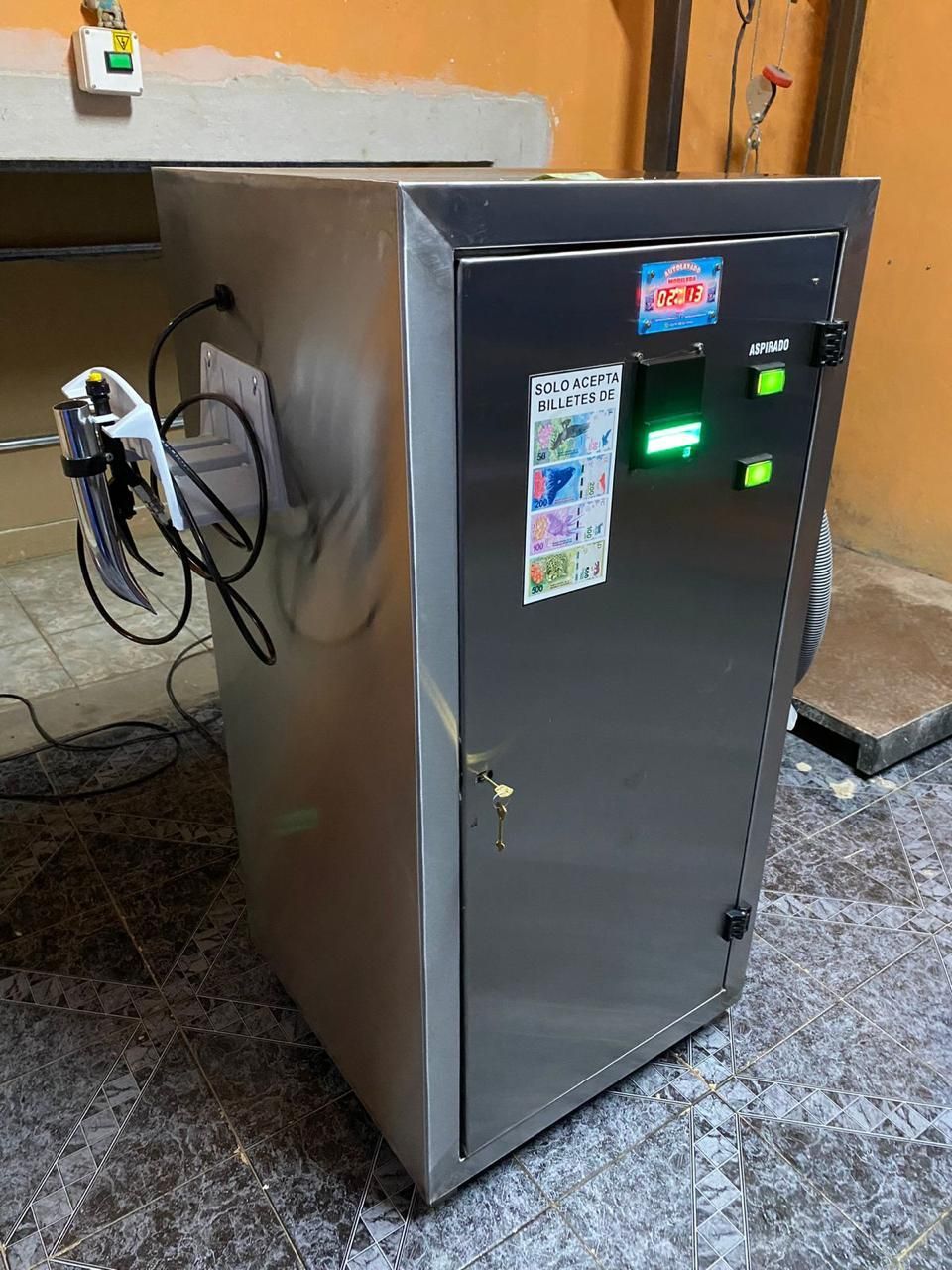 Armario de acero inoxidable con panel de control y boquilla acoplada en un entorno industrial.